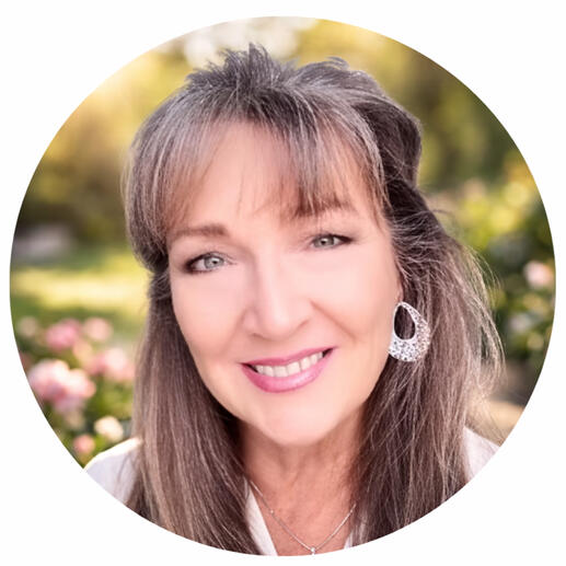 Author Portrait of the creator and author smiling in a garden with flowers in the background.